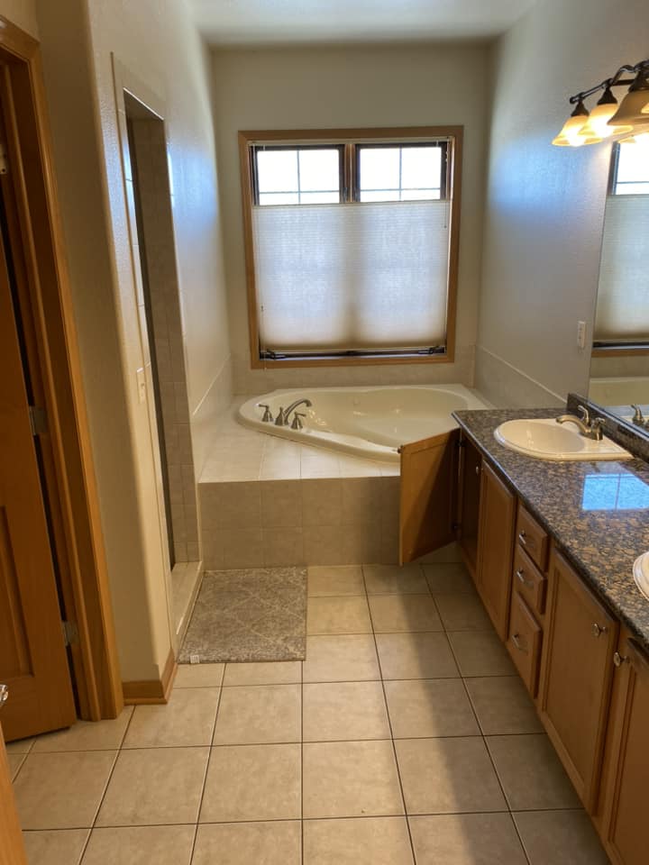 Existing master bathroom before renovation with corner jetted tub, walk-in shower entrance, and tile floor